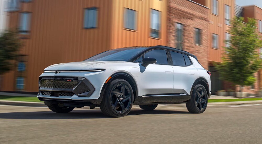 A white 2024 Chevy Equinox EV RS driving on a city street.