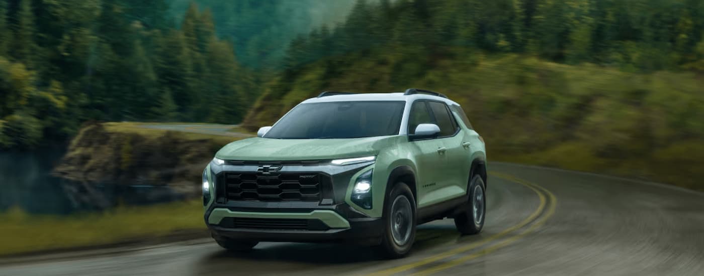 A green 2025 Chevy Equinox ACTIV driving on a rainy day.