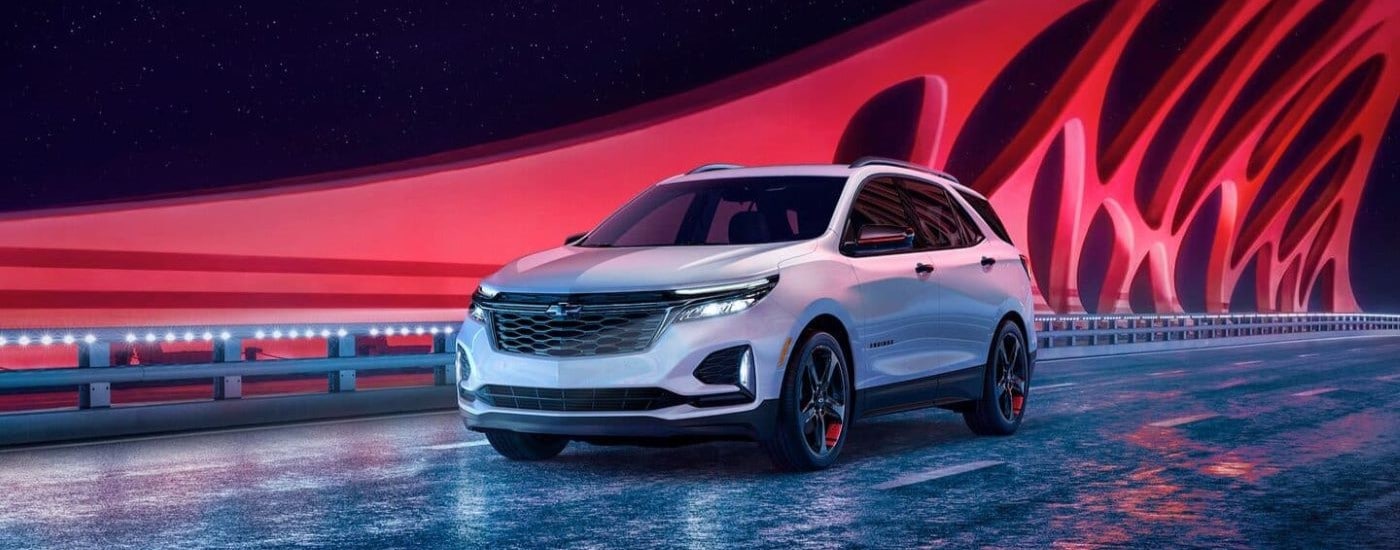 A white 2024 Chevy Equinox Redline driving across a bridge from a Chevy dealer near Greenfield.