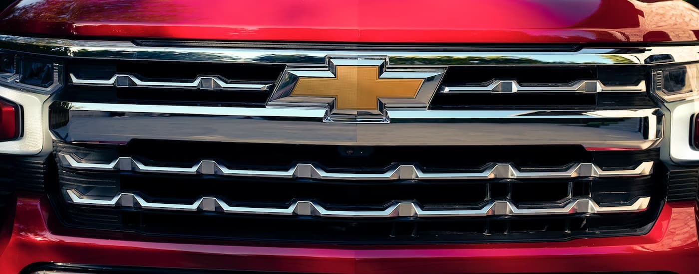 A close up of the grille on a red 2023 Chevy Silverado 1500 LTZ is shown at a Chevy dealership near Pittsfield.