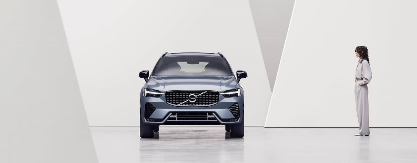 A metallic 2025 Volvo XC60 is shown parked indoors near a person.