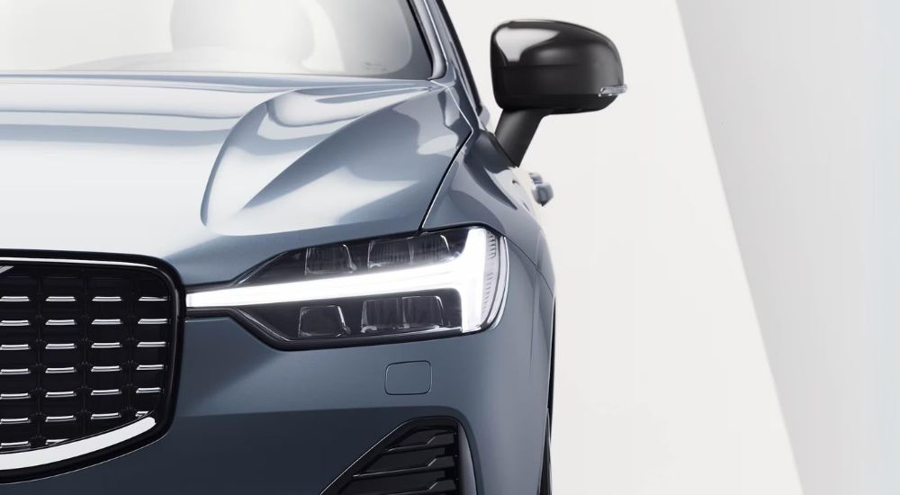 A close up shows the headlight on a blue 2024 Volvo XC60 for sale.