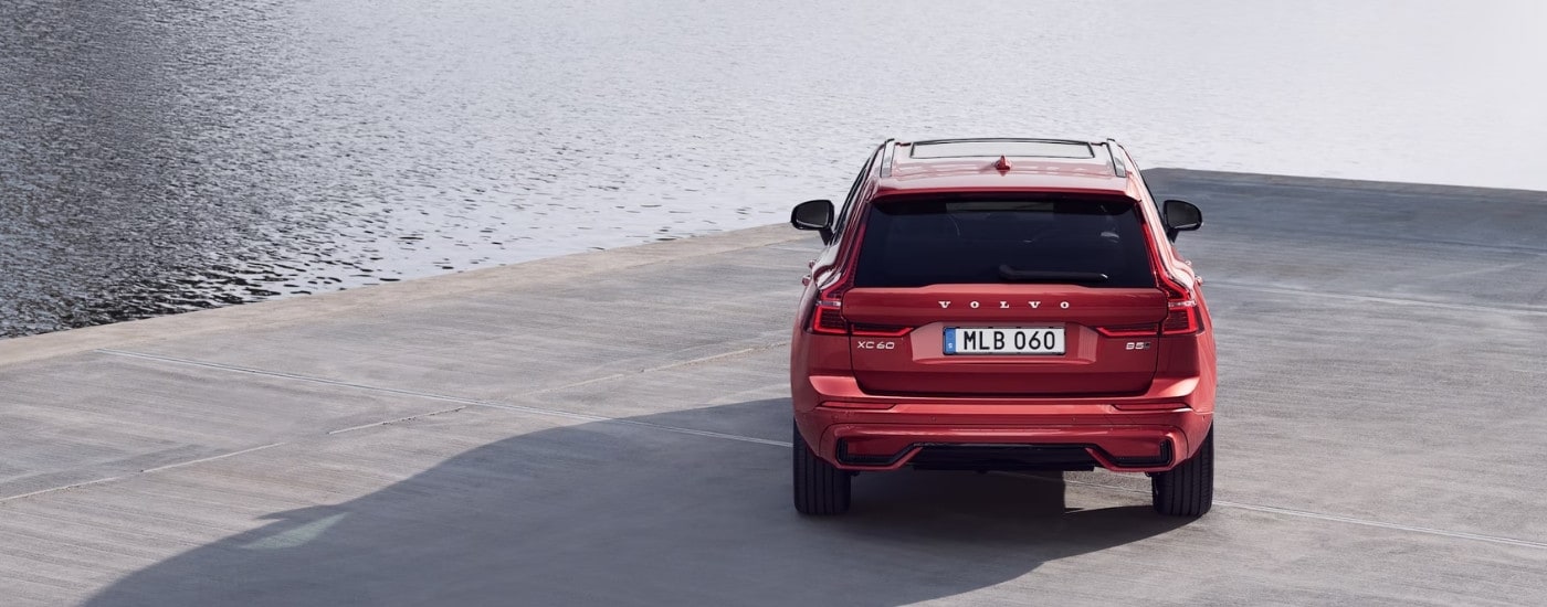 Rear view of a red 2025 Volvo XC60 for sale parked on a concrete pier.