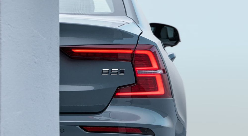 A close-up shows the passenger side taillight on a blue 2024 Volvo S60 B5.