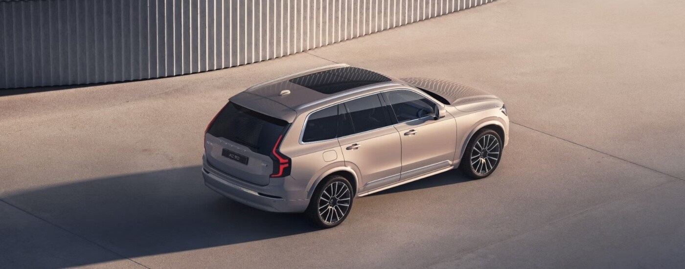 A tan 2025 Volvo XC90 is shown from the rear at an angle.
