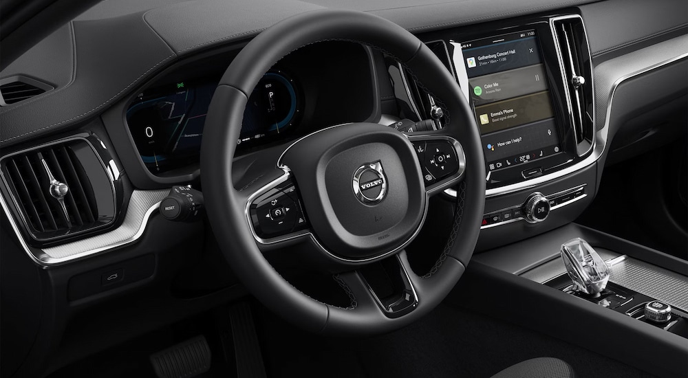A close-up of the steering wheel and black interior of a 2024 Volvo S60 at a Volvo dealer near Lee.