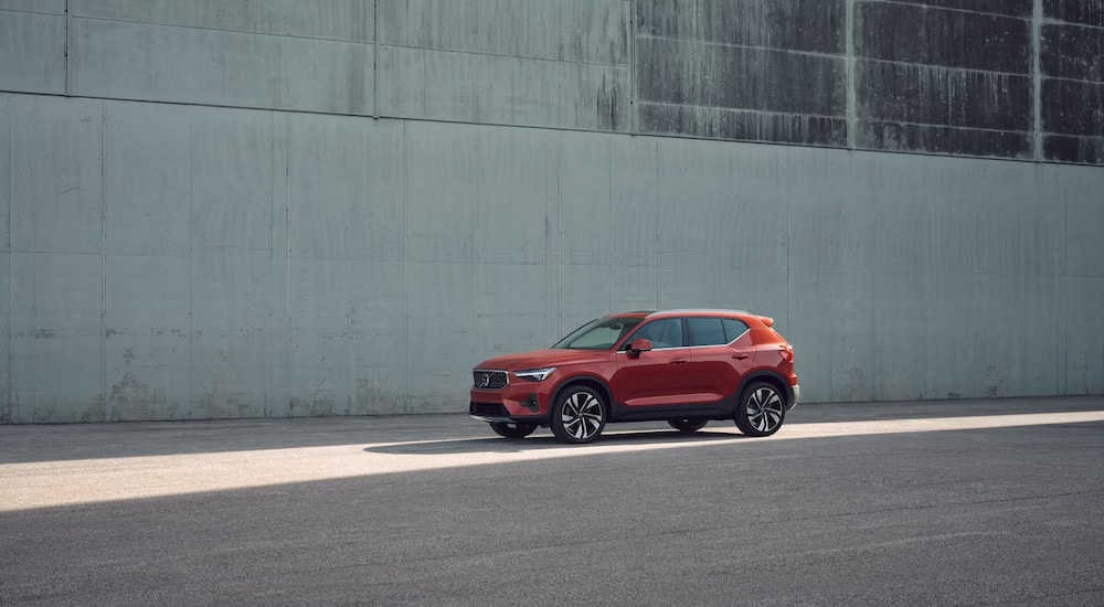 A red 2024 Volvo XC40 parked in front of a large blank wall.