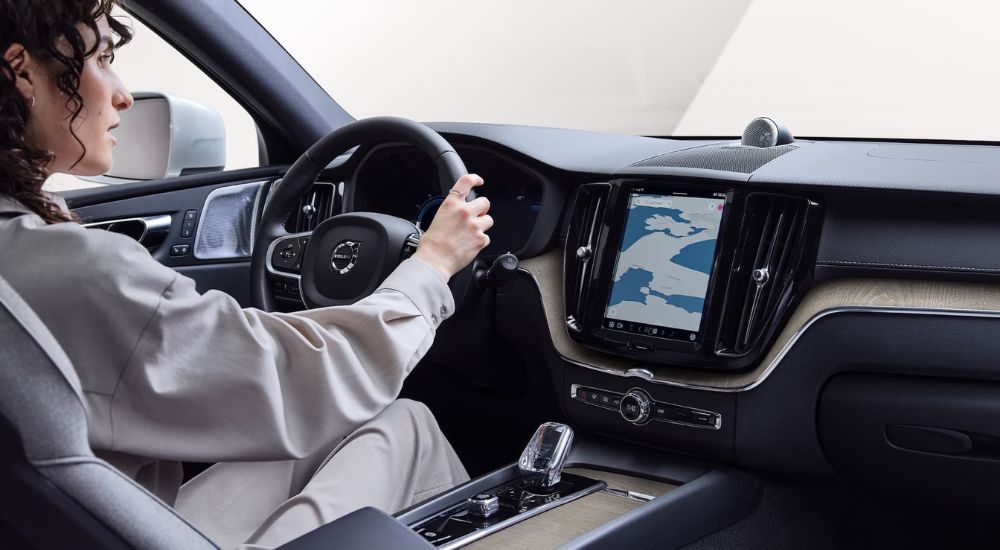 A person is shown driving a 2024 Volvo XC60 Recharge to a Volvo dealership.