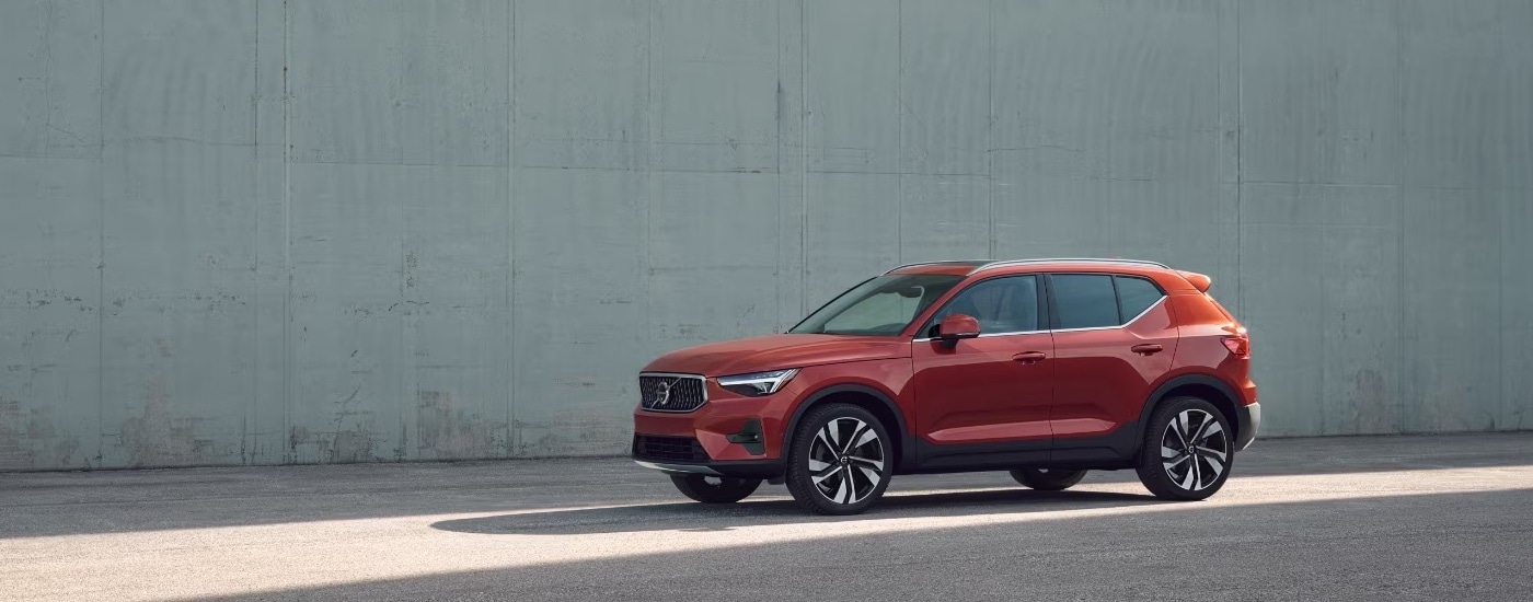 Volvo%20Dealer%20Near%20Stockbridge%20-%202024%20Volvo%20XC40%20-%20Side%20Wall.jpeg Side view of a red 2024 Volvo XC40 parked in front of a tall concrete wall.
