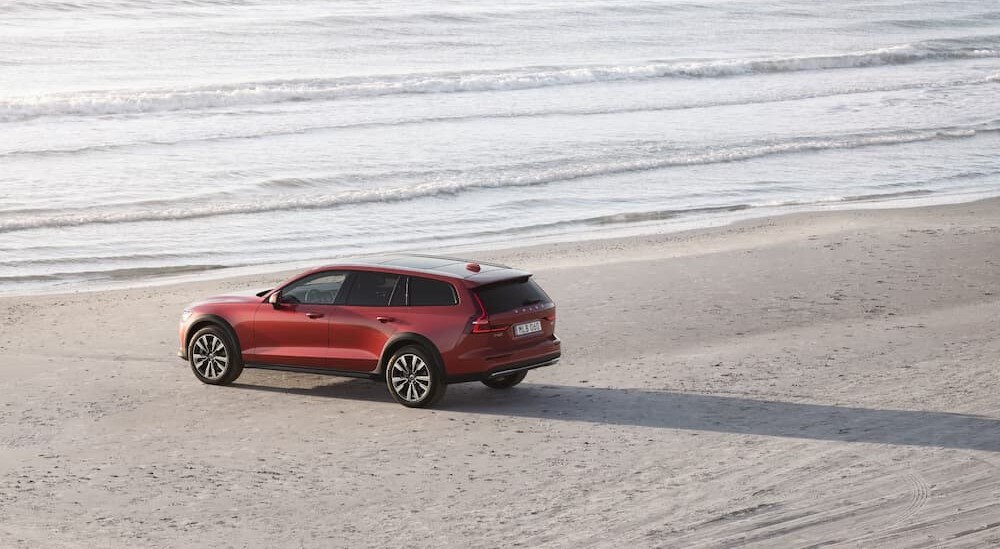 A red 2025 Volvo V60 Cross Country for sale is shown parked on a beach.