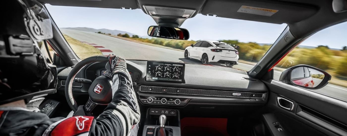 A race car driver is shown in a red 2023 Honda Civic Type R on a race track.
