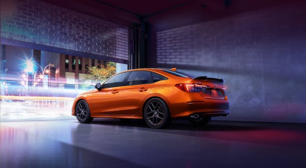 An orange 2024 Honda Civic Si is shown from the side while parked after leaving a Honda dealership.