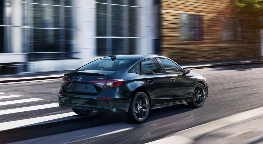 A black 2025 Honda Civic Hybrid Sport is shown driving on a city street.