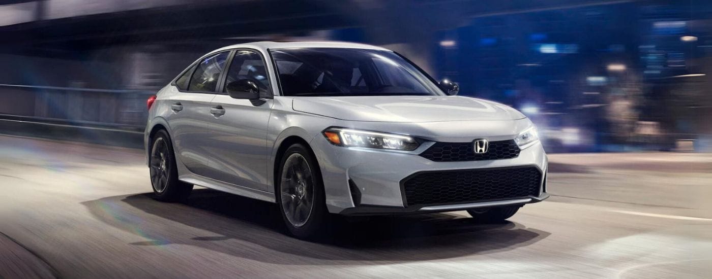 A white 2025 Honda Civic Hybrid Sport is shown driving to a Honda dealer near Greenfield.