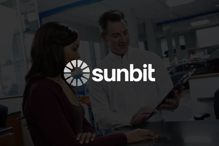 Sunbit logo overlayed on top of an image of a Honda service advisor talking with a customer