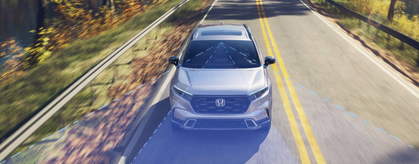 Simulated Honda Sensing lines projecting from a silver 2024 Honda CR-V Sport Touring Hybrid.