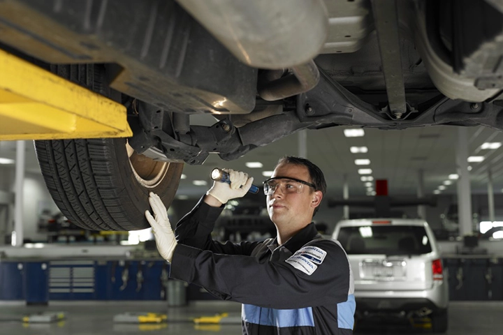 Honda service technician examining the underside of a vehicle on a lift