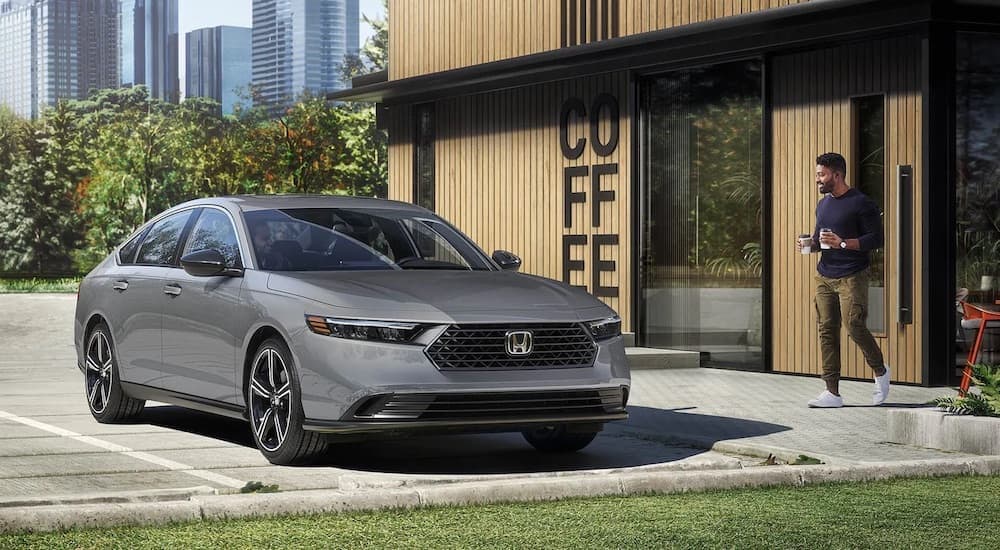 A grey 2024 Honda Accord Hybrid is shown near a coffee shop after leaving a Honda dealership near North Adams.