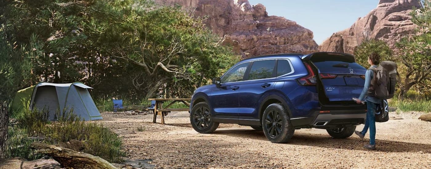 A blue 2025 Honda CR-V Sport Touring is shown parked on a campsite.
