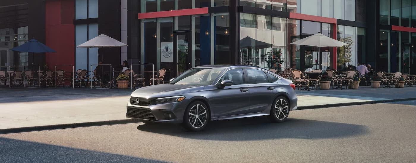 A grey 2024 Honda Civic is parked in front of a cafe after leaving a Honda dealership near Bennington.