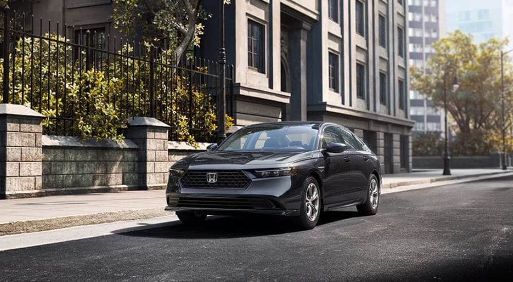 2024%20Honda%20Accord%20EX%20-%20Fence%202.jpg A gray 2024 Honda Accord EX is shown driving on a city street after viewing a Honda Accord for sale.