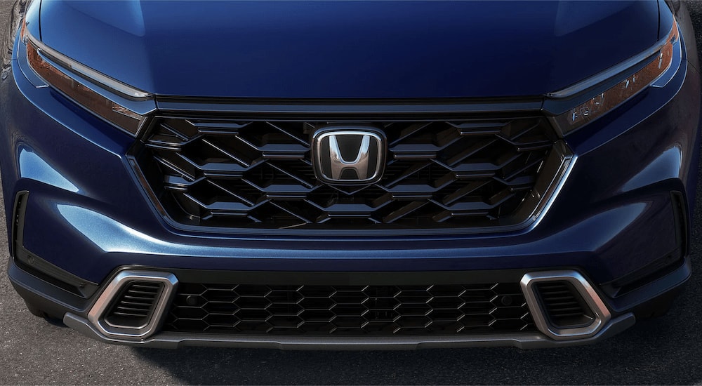 A close up of the front grille on a blue 2025 Honda CR-V Sport Touring Hybrid for sale.