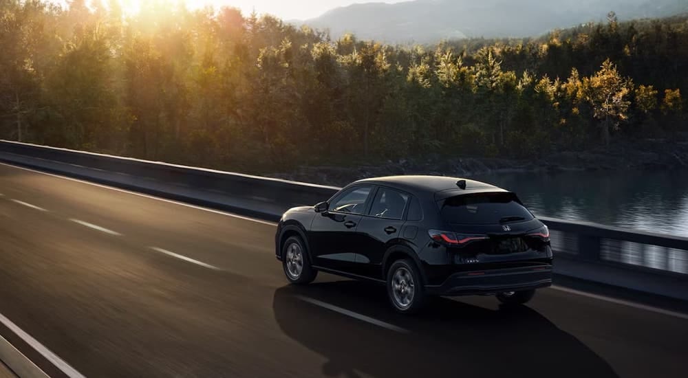 A black 2024 Honda HR-V is driving over a bridge.