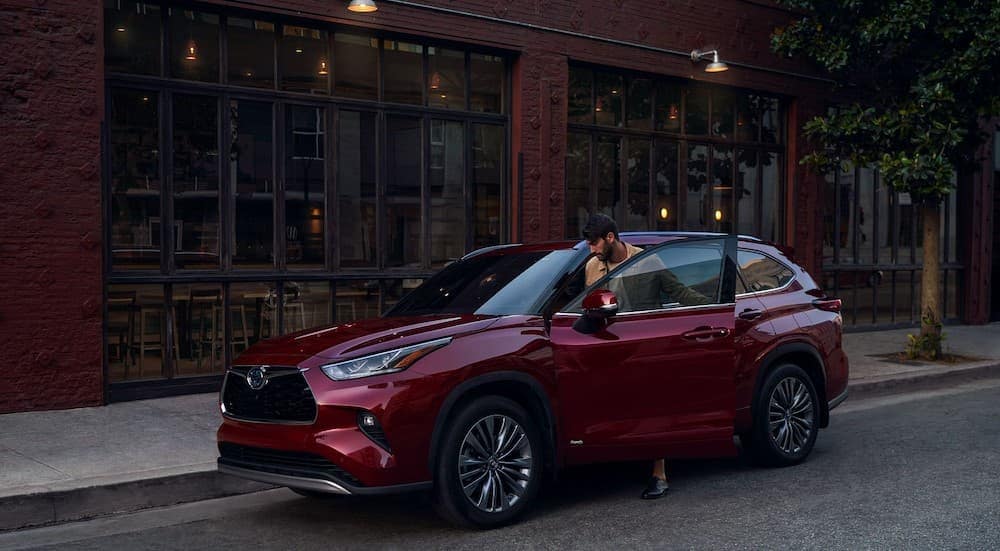 A red 2025 Toyota Highlander is shown parked on a city street.