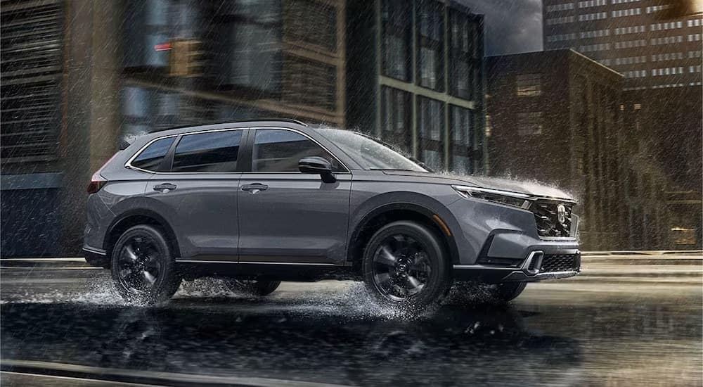 A grey 2024 Honda CR-V is shown from the side in the rain.
