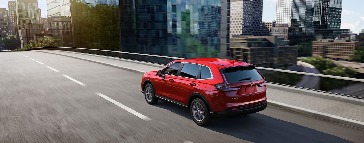 A red 2024 Honda CR-V EX is shown from the rear driving on a highway after leaving a Honda dealership near Pittsfield.