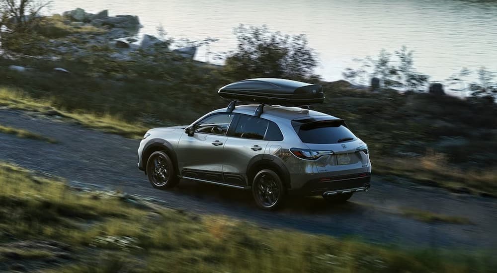 A silver 2024 Honda HR-V HPD is shown from the rear at an angle on a trail after leaving a Honda dealership.