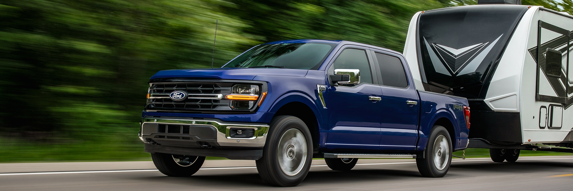 Blue 2026 Ford F-150 towing a travel trailer. $4,500 Total Cash on 2026 F-150 STX, XLT and Lariat at Bell Ford in Arlington, Wisconsin.