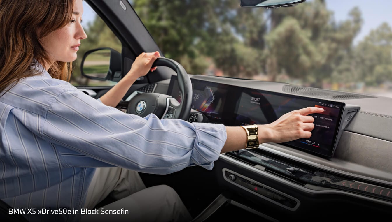 A woman touching the infotainment screen in her BMW X5 xDrive50e