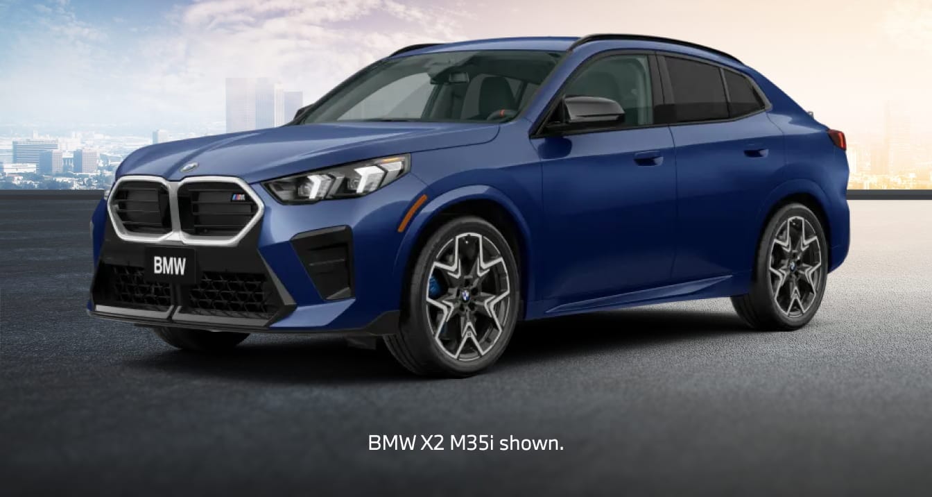 A blue BMW X2 M35i SUV shown from a front three-quarter angle on a paved surface, with a city skyline in the background.