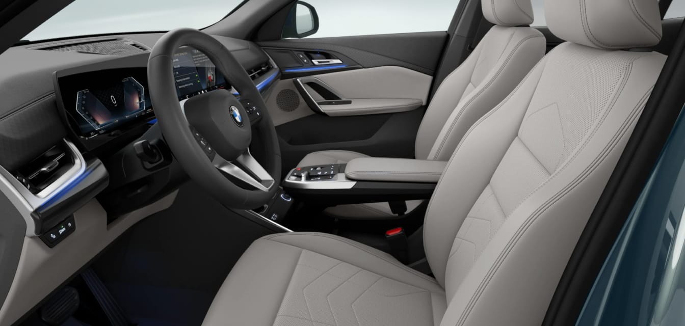 A view of the BMW X2 front interior featuring light-colored front seats, a multifunction steering wheel and a modern center console.