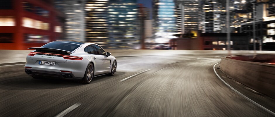 Begin Your Ownership Experience A Porsche Panamera driving around a cruved highway