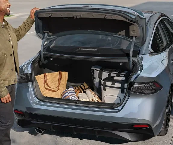 Loading suitcases into a Nissan Sentra trunk, showing the 14.3 cubic foot cargo space