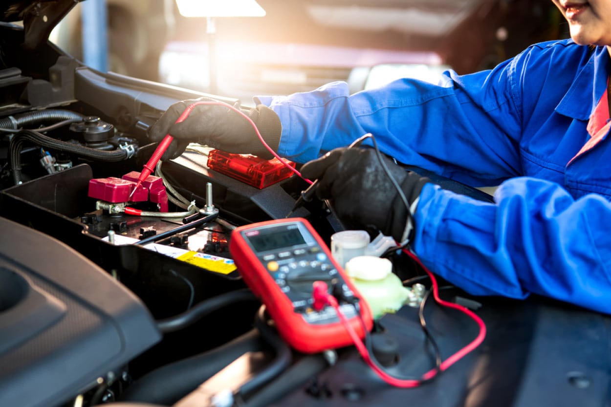 A Bison Ford technician performing a load test on a car battery in cold, snowy conditions.