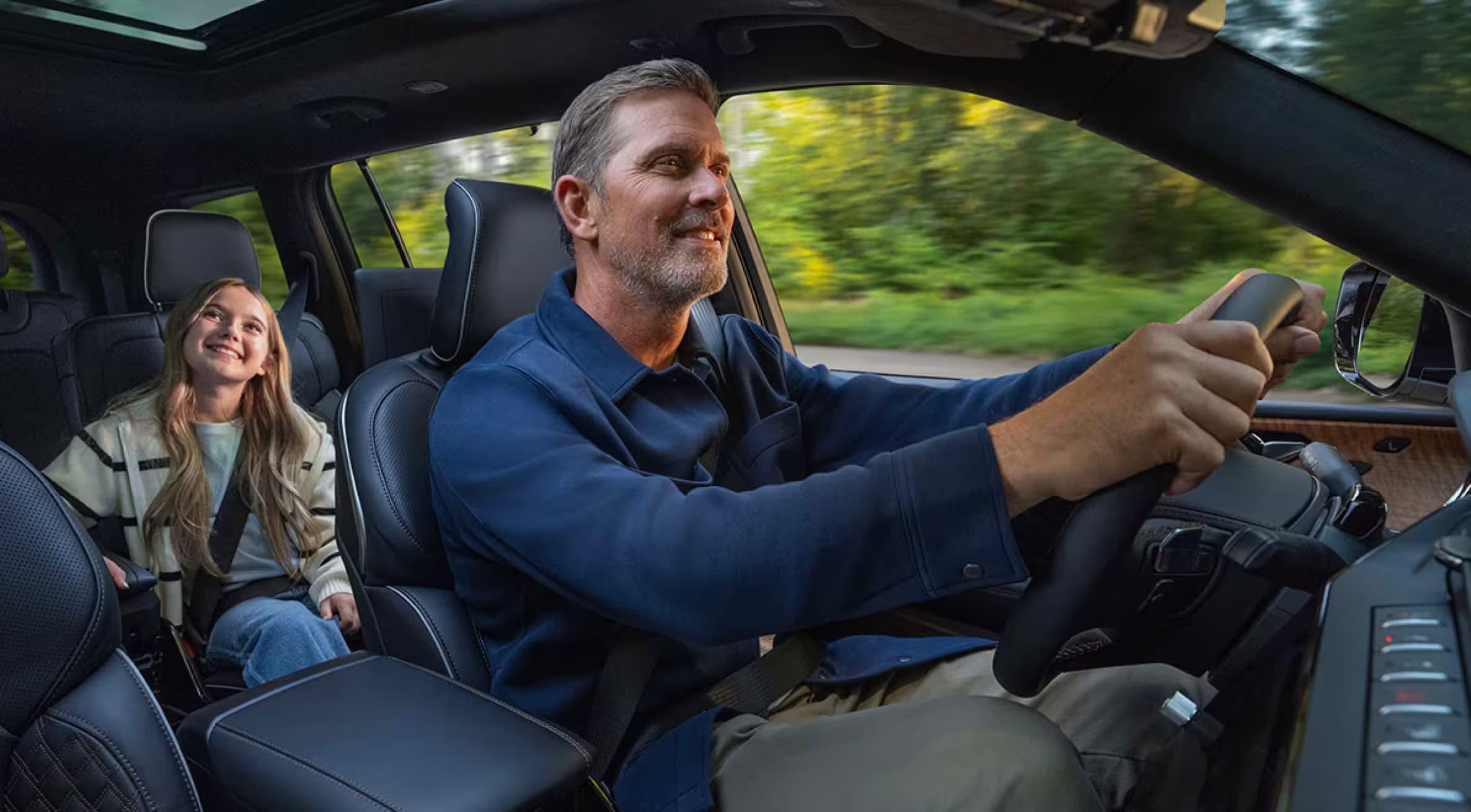 Man driving a Jeep Grand Cherokee with a child in rear seat