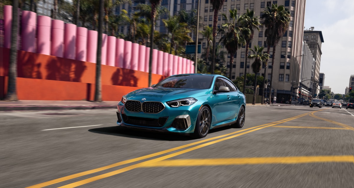 
A blue metallic BMW 2 Series Gran Coupe driving down
street during the day.