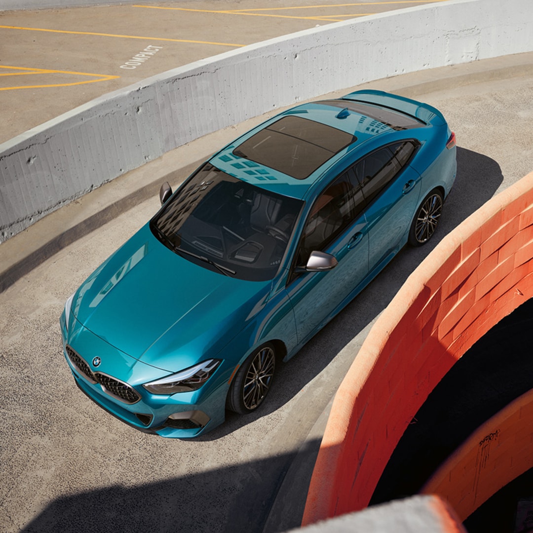 A blue metallic BMW 2 Series Gran Coupe driving down
parking garage ramp.
