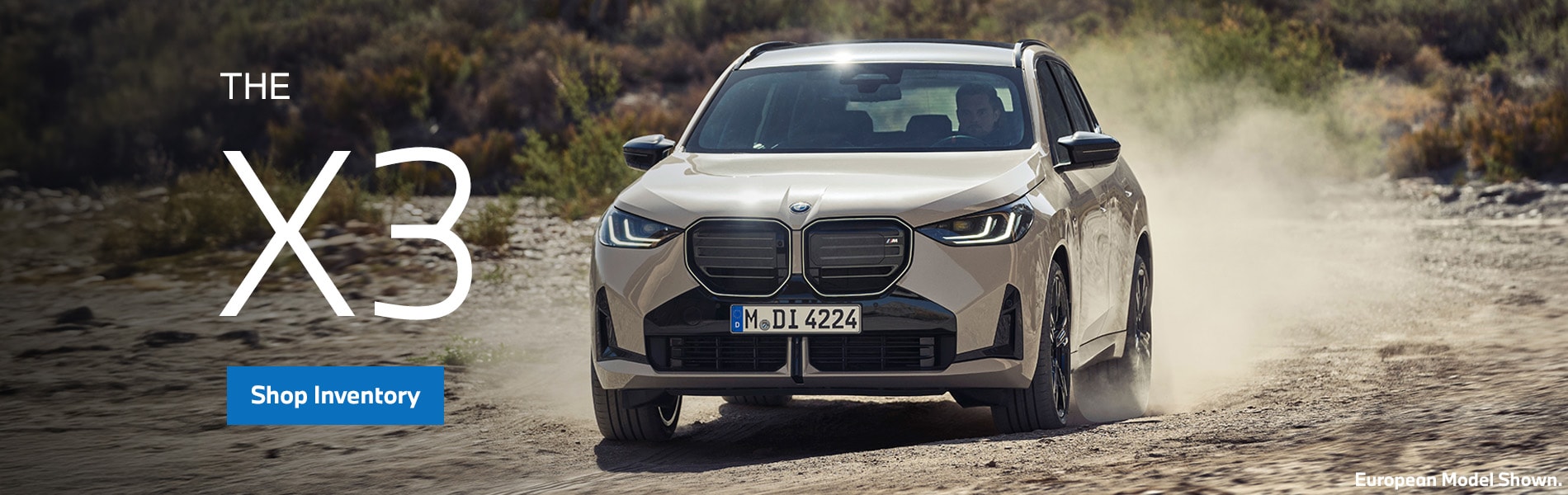 BMW X3 driving on dirt orad parked with a forest
landscape.
