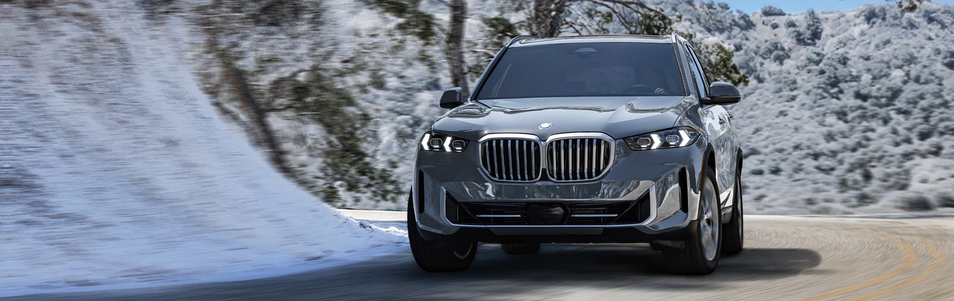  BMW X5 driving on a neighborhood road.