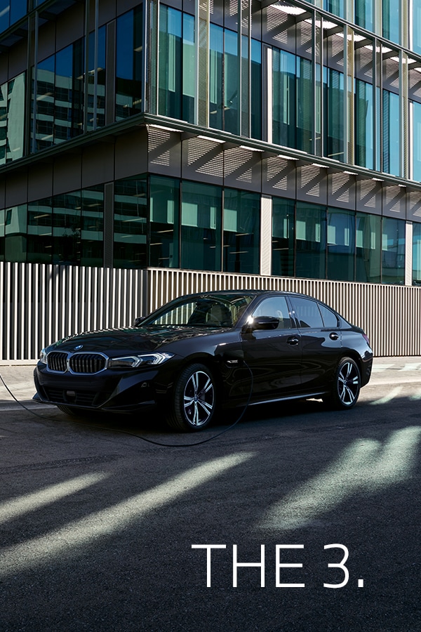 black BMW three series parked in front of city building.