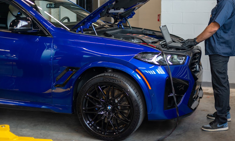 Technician servicing a blue BMW in the service bay