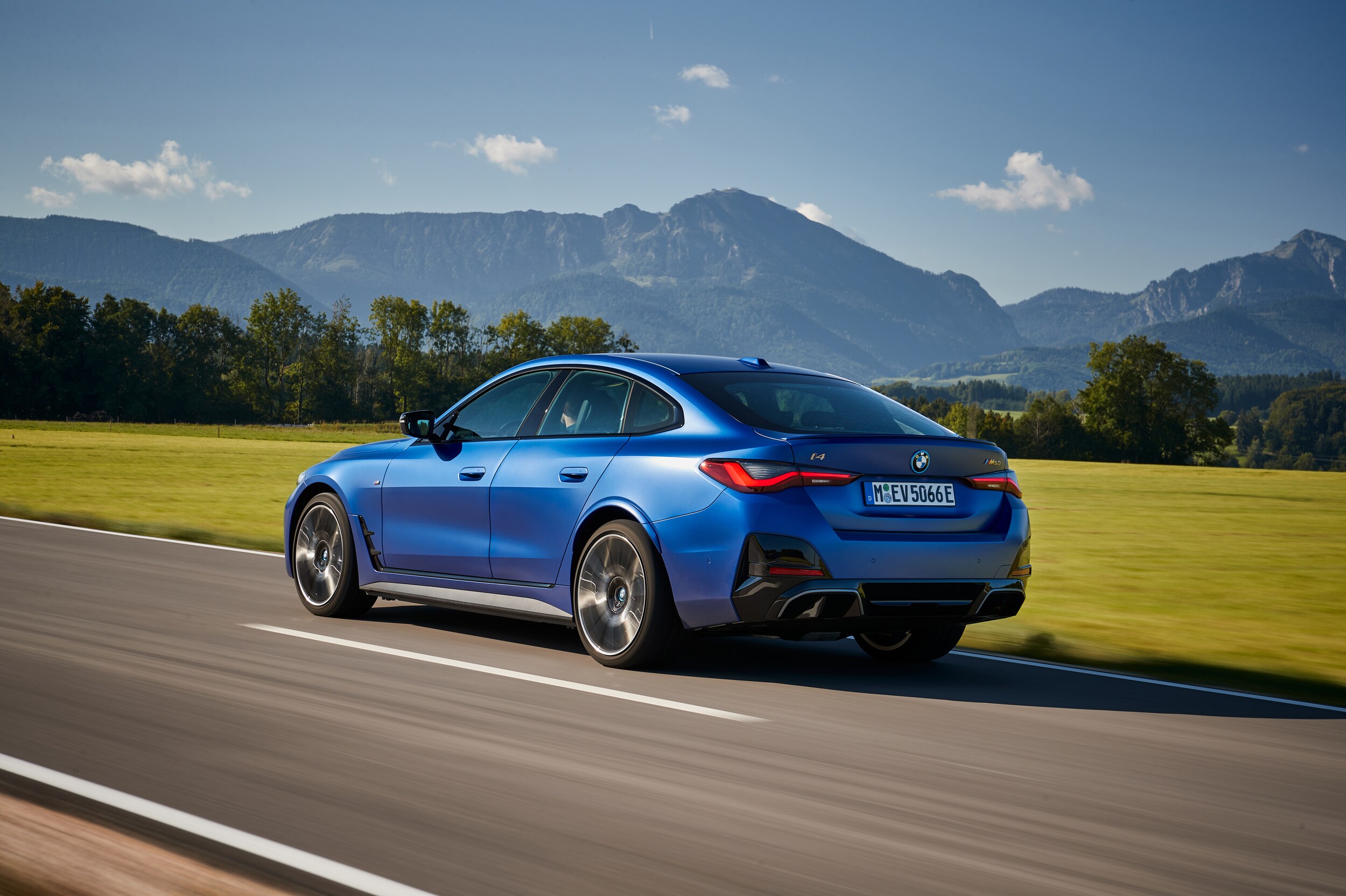 Blue BMW drives down road on a sunny day