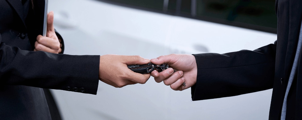 Person trading in keys to car dealership salesman