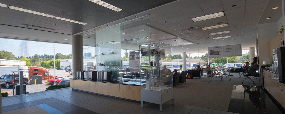 BMW of Bellevue interior. Glass display case, tall windows, and tables with chairs are all in frame.