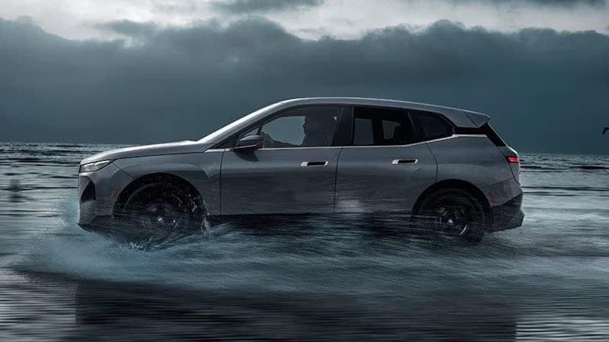 Side view of a BMW iX driving through rain