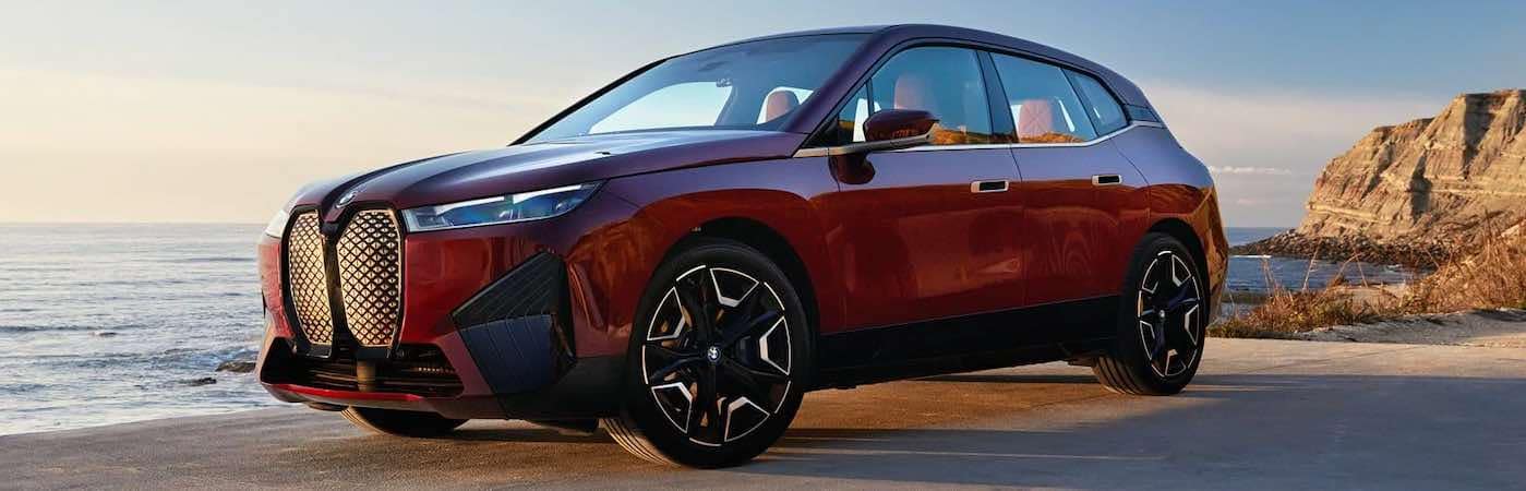 Red BMW iX on a beach in the sun